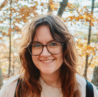 Woman with glasses smiling outdoors in autumn